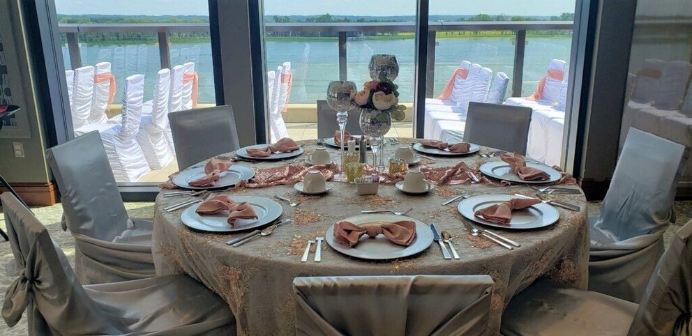 Banquet table set with pink accents and set in front of a large window showcasing The Merrill Hotels balcony with the Mississippi River in the background