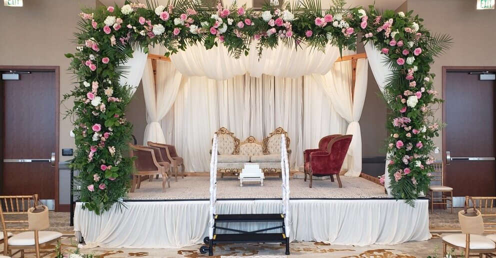 Wedding ceremony setup with floral arch covering stage